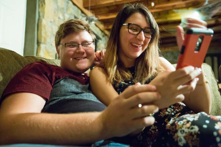 Zach Eason, 20, and Luz Skywalker, 21, look at a phone together while relaxing in entertainment room of Eason's home on Tuesday.