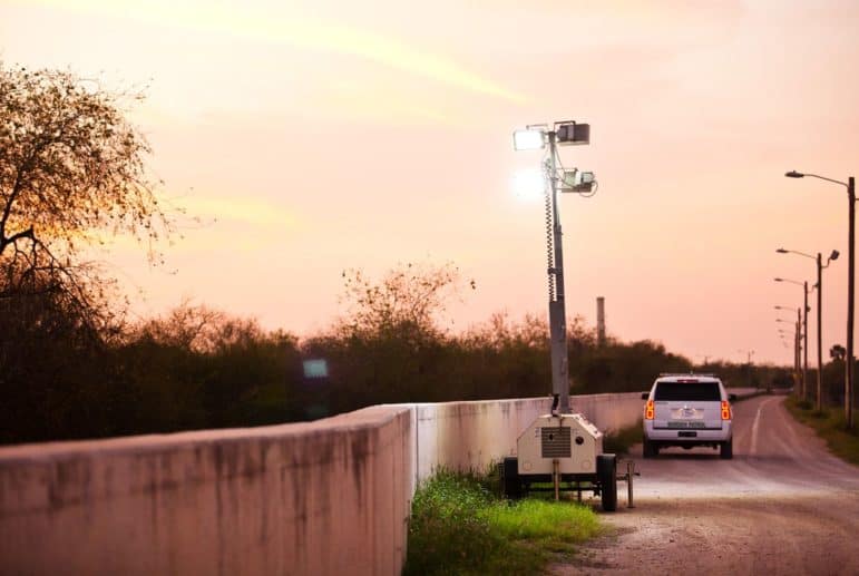 At dusk, Border Patrol agents place mobile floodlights along the levee-fence in Hidalgo County.